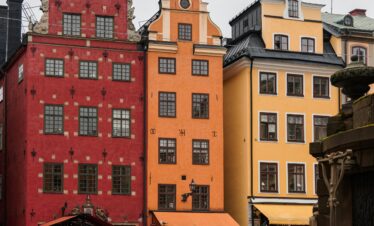 Vibrant facades in Stockholm's Gamla Stan with people in the square below on a cloudy day.