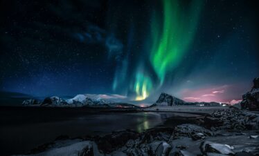 Breathtaking view of the Northern Lights illuminating the snowy landscape of Nordland, Norway.